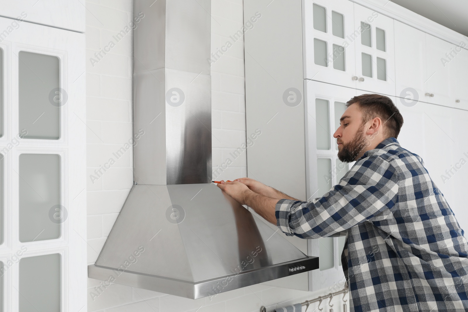 Photo of Man repairing modern cooker hood in kitchen