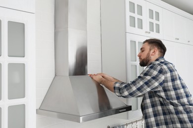 Photo of Man repairing modern cooker hood in kitchen