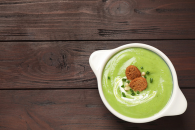 Photo of Tasty homemade zucchini cream soup on wooden table, top view. Space for text