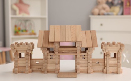 Wooden entry gate on white table indoors. Children's toy