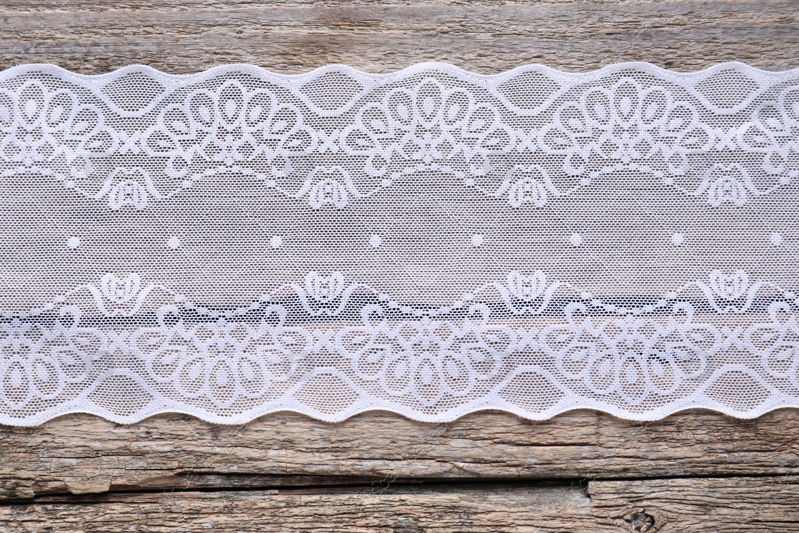 Photo of White lace on wooden table, top view