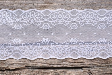 Photo of White lace on wooden table, top view