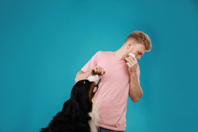 Young man suffering from fur allergy on blue background