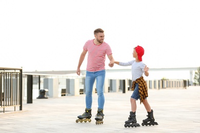 Father and son roller skating on city street