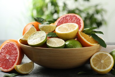 Photo of Different fresh citrus fruits and leaves on table against blurred background, closeup