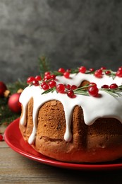 Photo of Traditional Christmas cake decorated with glaze, pomegranate seeds, cranberries and rosemary on wooden table