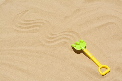 Plastic rake on sand, space for text. Beach toy