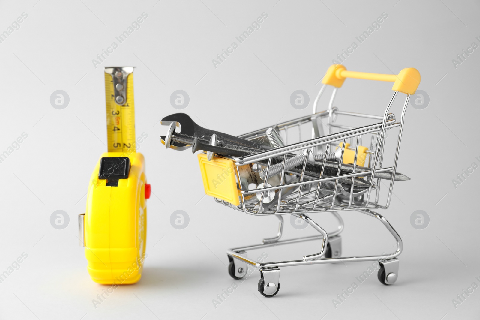 Photo of Shopping cart with different construction tools on light grey background