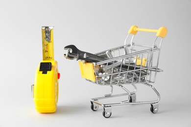 Photo of Shopping cart with different construction tools on light grey background