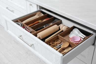 Photo of Open drawer with utensil set indoors. Order in kitchen
