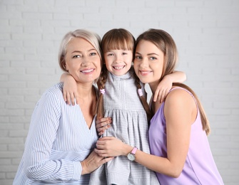 Photo of Beautiful mature woman with daughter and grandchild near brick wall