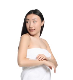 Beautiful young Asian woman applying body cream onto arm on white background