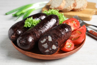 Photo of Tasty blood sausages served on white wooden table, closeup