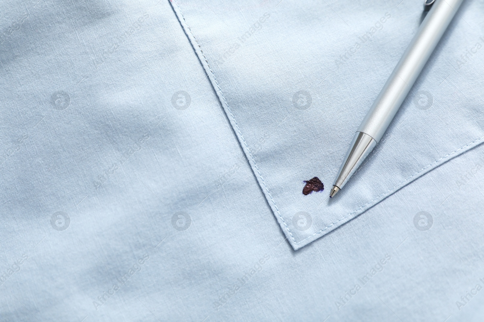 Photo of Pen and stain of black ink on light shirt, top view. Space for text