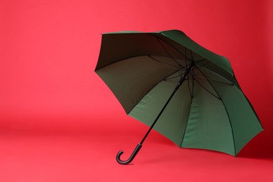 Photo of Stylish open green umbrella on red background. Space for text