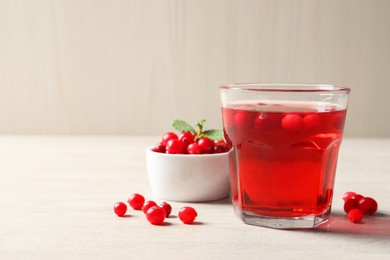 Photo of Tasty refreshing cranberry juice and fresh berries on light wooden table. Space for text