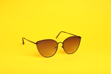 Photo of Stylish pair of sunglasses on yellow background