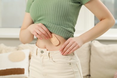 Photo of Woman applying contraceptive patch onto her body indoors, closeup