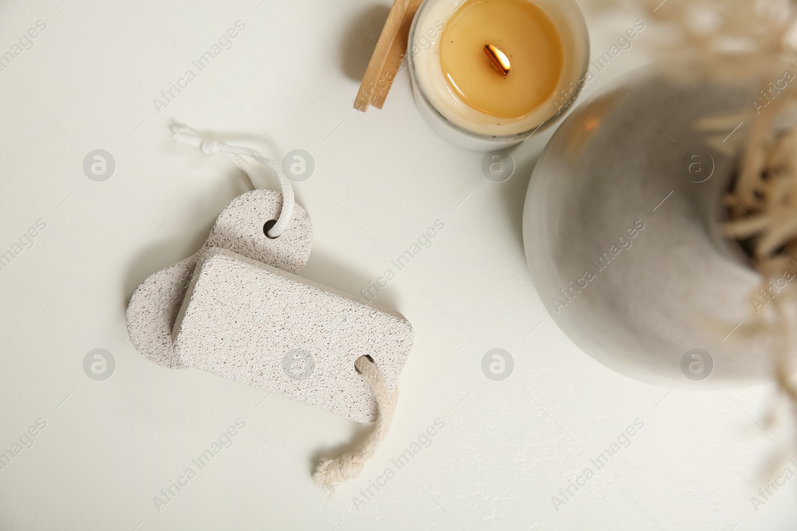 Photo of Pumice stones, candle and vase on white table, flat lay