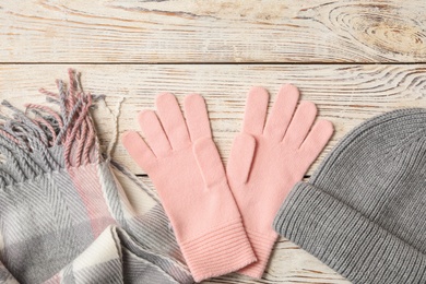 Stylish pink woolen gloves, scarf and hat on white wooden table, flat lay