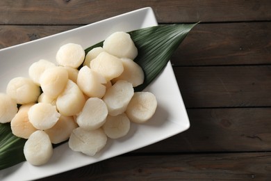 Photo of Fresh raw scallops on wooden table, top view. Space for text