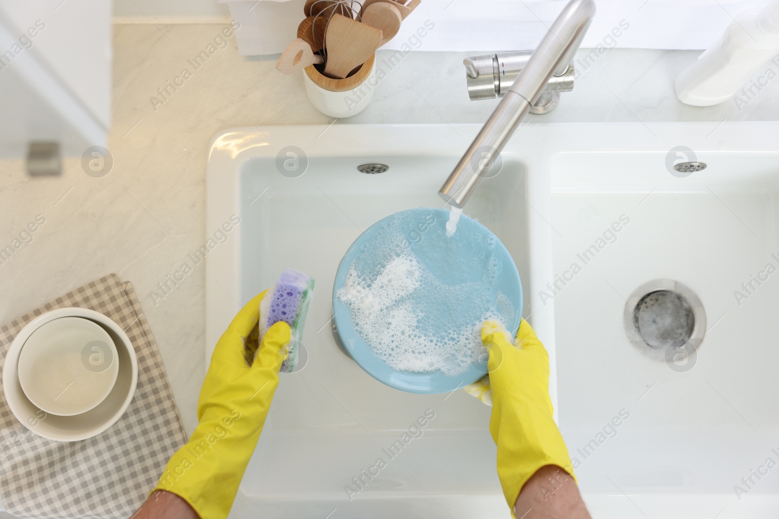 Photo of Man washing plate in kitchen sink, top view