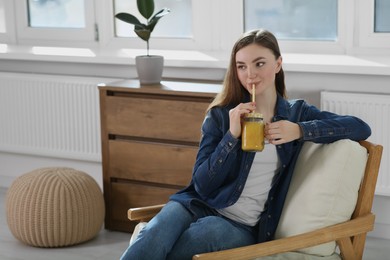 Beautiful young woman drinking delicious smoothie at home. Space for text