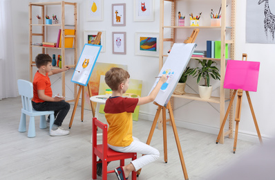 Photo of Cute little children painting during lesson in room