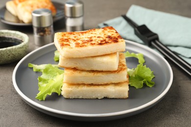 Photo of Delicious turnip cake with lettuce salad served on grey table
