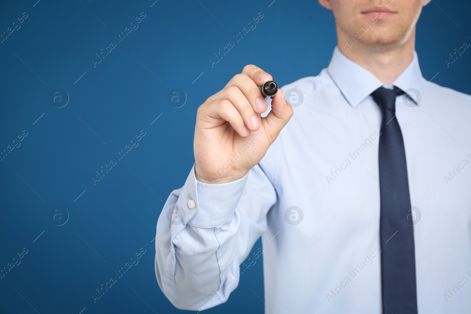 Photo of Businessman with marker against blue background, focus on hand. Space for text
