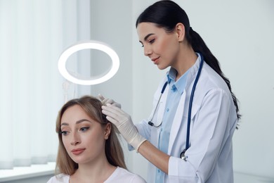 Photo of Young woman visiting trichologist in light clinic