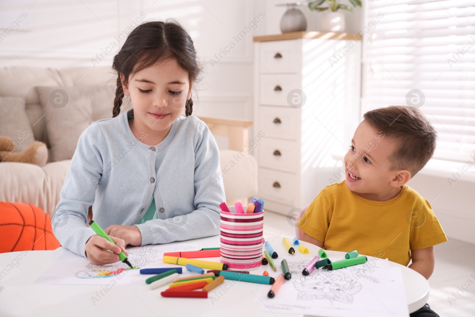 Photo of Cute children coloring drawings at table in room