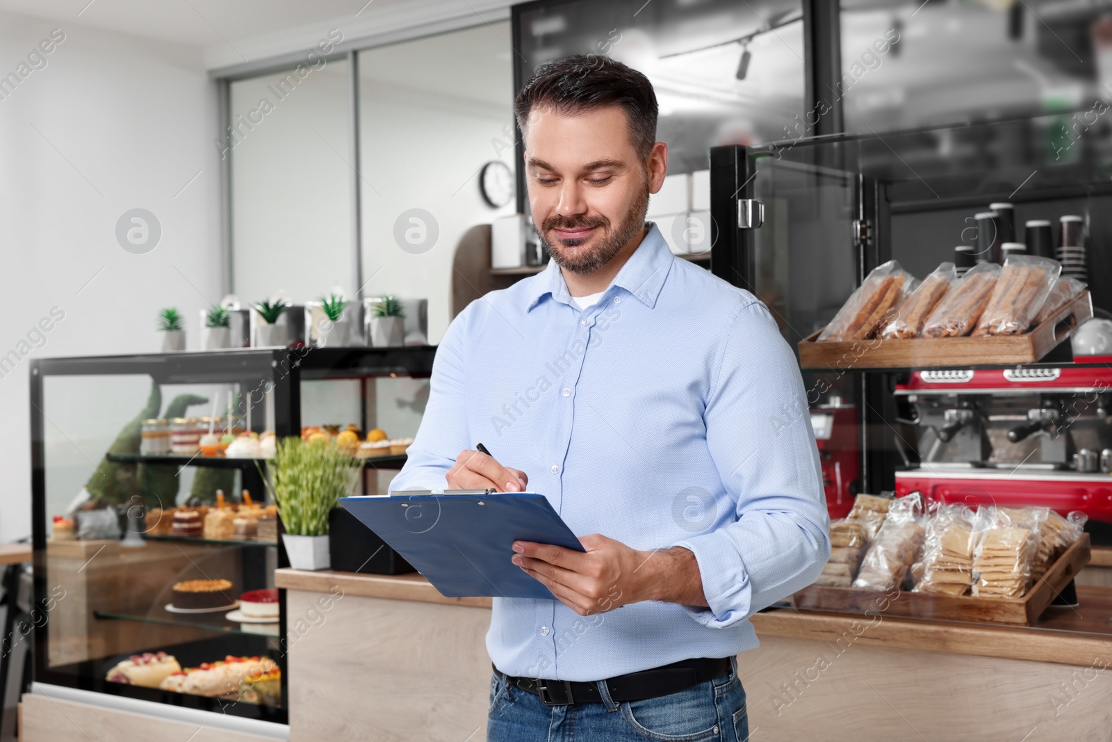 Photo of Business owner with clipboard in his cafe