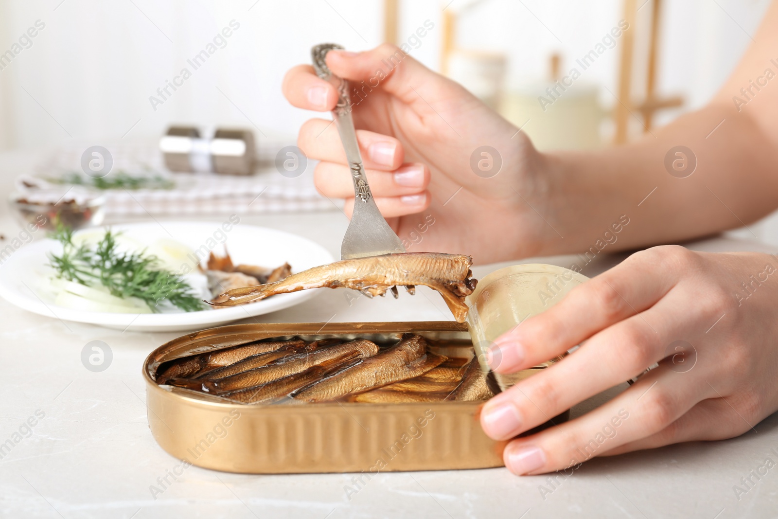 Photo of Woman with tin can of conserved fish at table