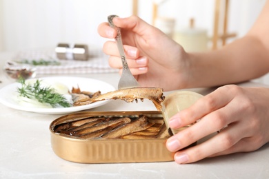 Photo of Woman with tin can of conserved fish at table