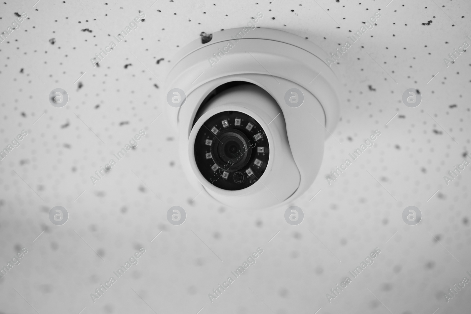 Photo of Modern CCTV camera on ceiling indoors, closeup