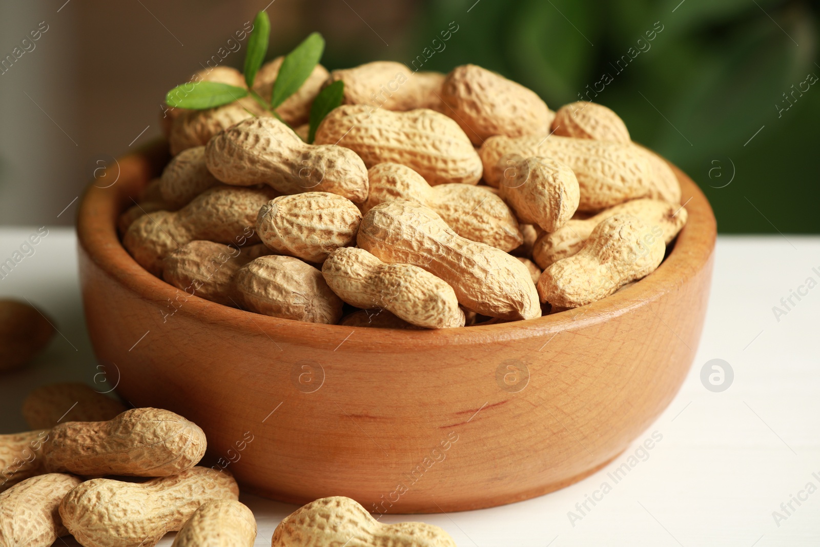 Photo of Fresh unpeeled peanuts in bowl on white table