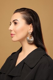 Photo of Portrait of young woman with beautiful makeup on light brown background