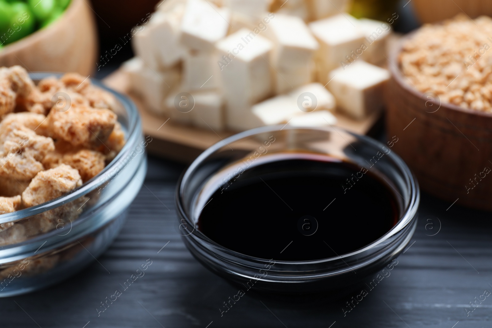 Photo of Soy sauce and other organic products on grey wooden table, closeup