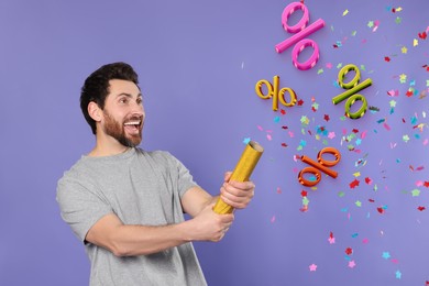 Image of Discount offer. Happy man blowing up party popper on violet background. Confetti and percent signs in air