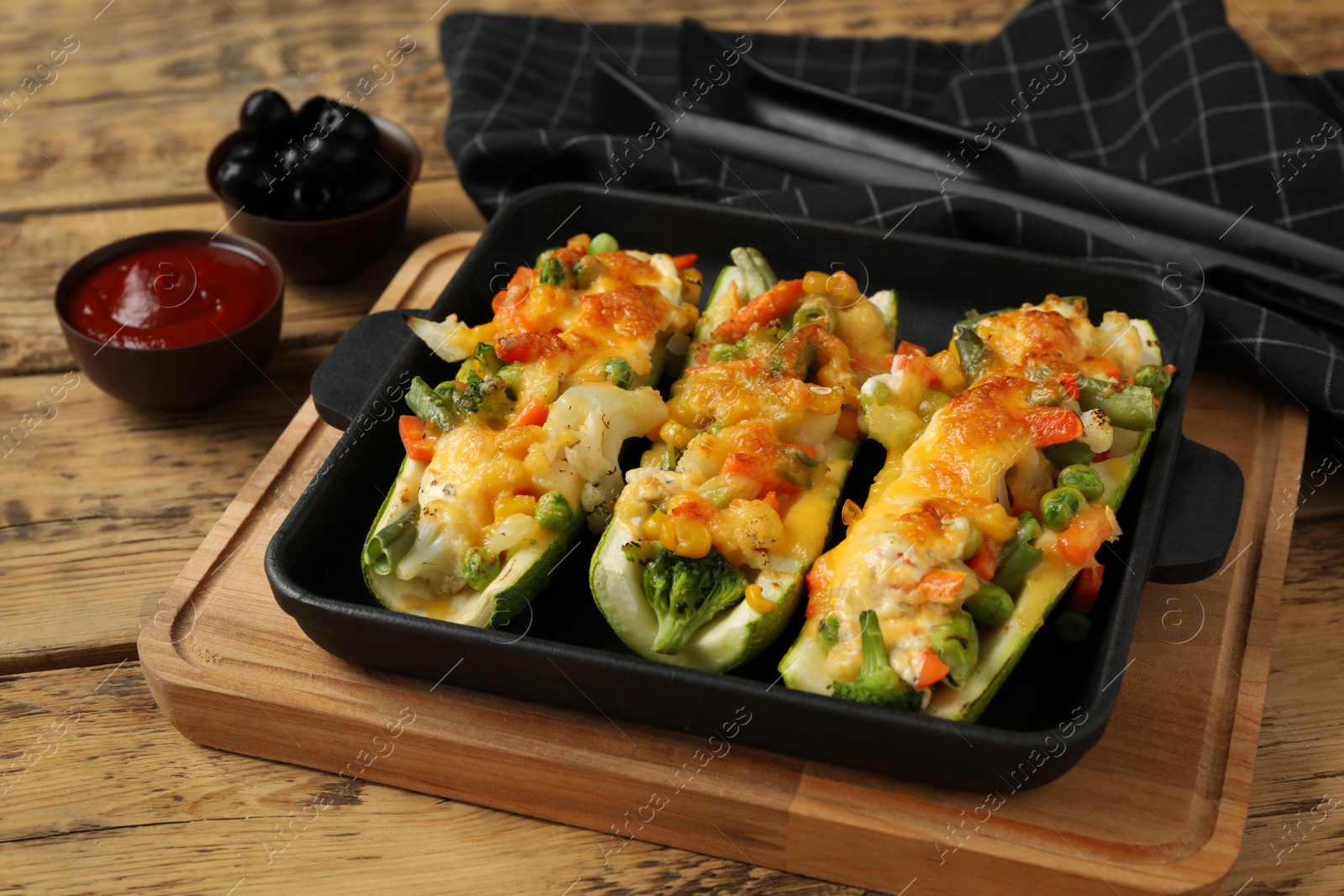 Photo of Baked stuffed zucchinis served on wooden table, closeup