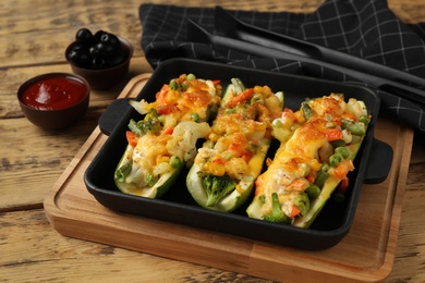 Photo of Baked stuffed zucchinis served on wooden table, closeup