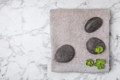 Photo of Fresh towel, flowers and spa stones on white marble background, flat lay. Space for text