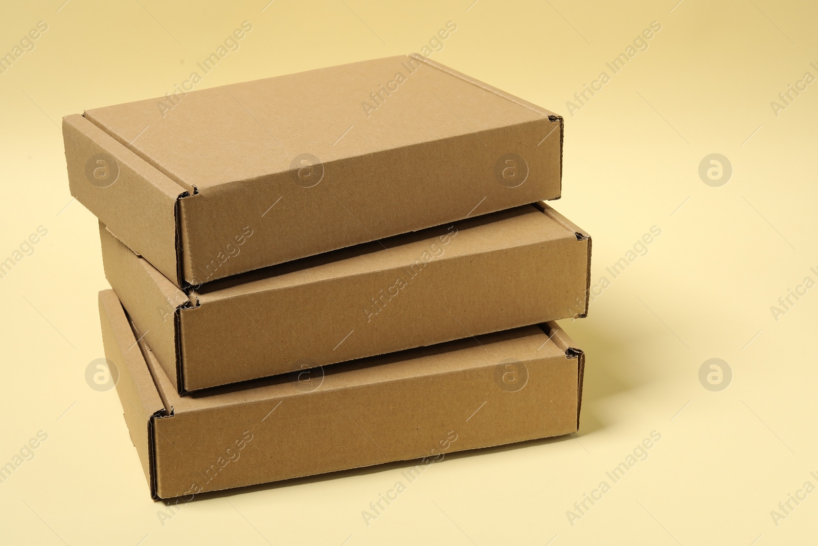 Photo of Stack of closed cardboard boxes on pale yellow background