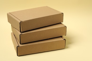 Stack of closed cardboard boxes on pale yellow background