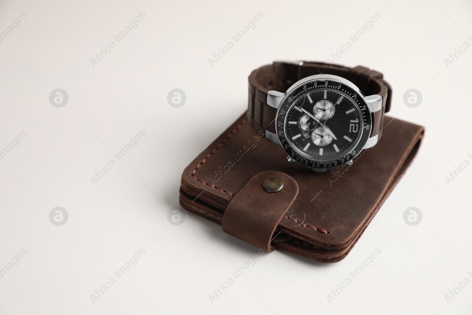 Photo of Stylish leather wallet and wristwatch on light background. Space for text