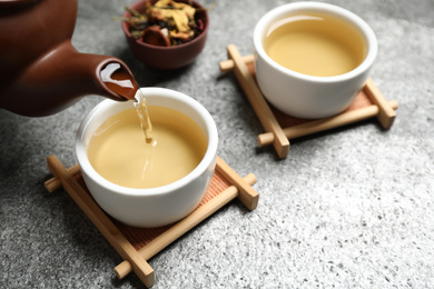 Photo of Pouring green tea into cup on grey table
