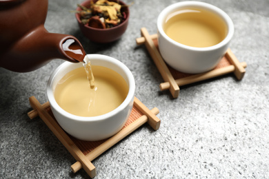 Pouring green tea into cup on grey table