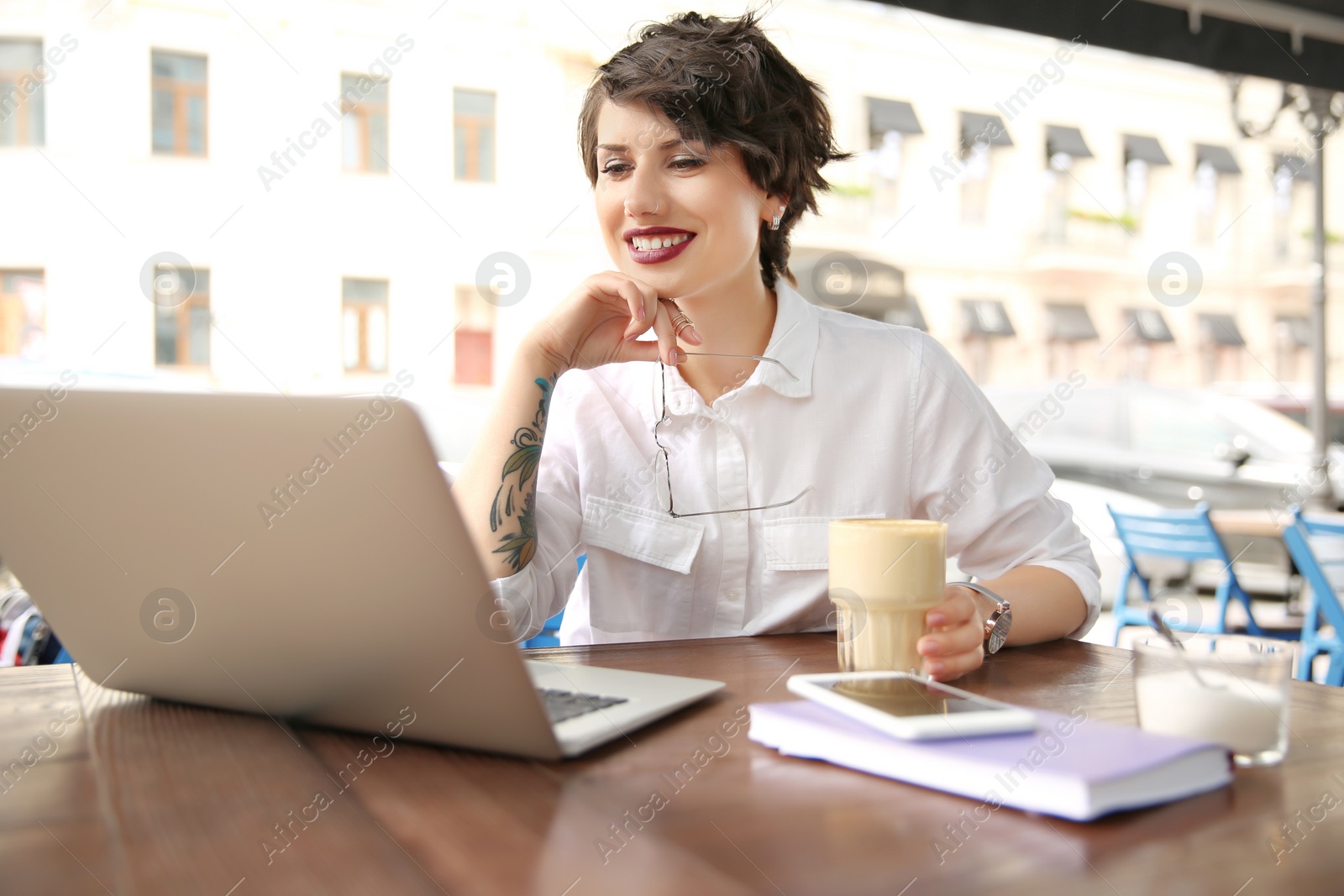 Photo of Young woman working with laptop at desk in cafe