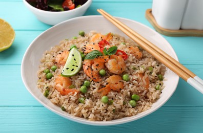 Tasty rice with shrimps and vegetables on turquoise wooden table, closeup